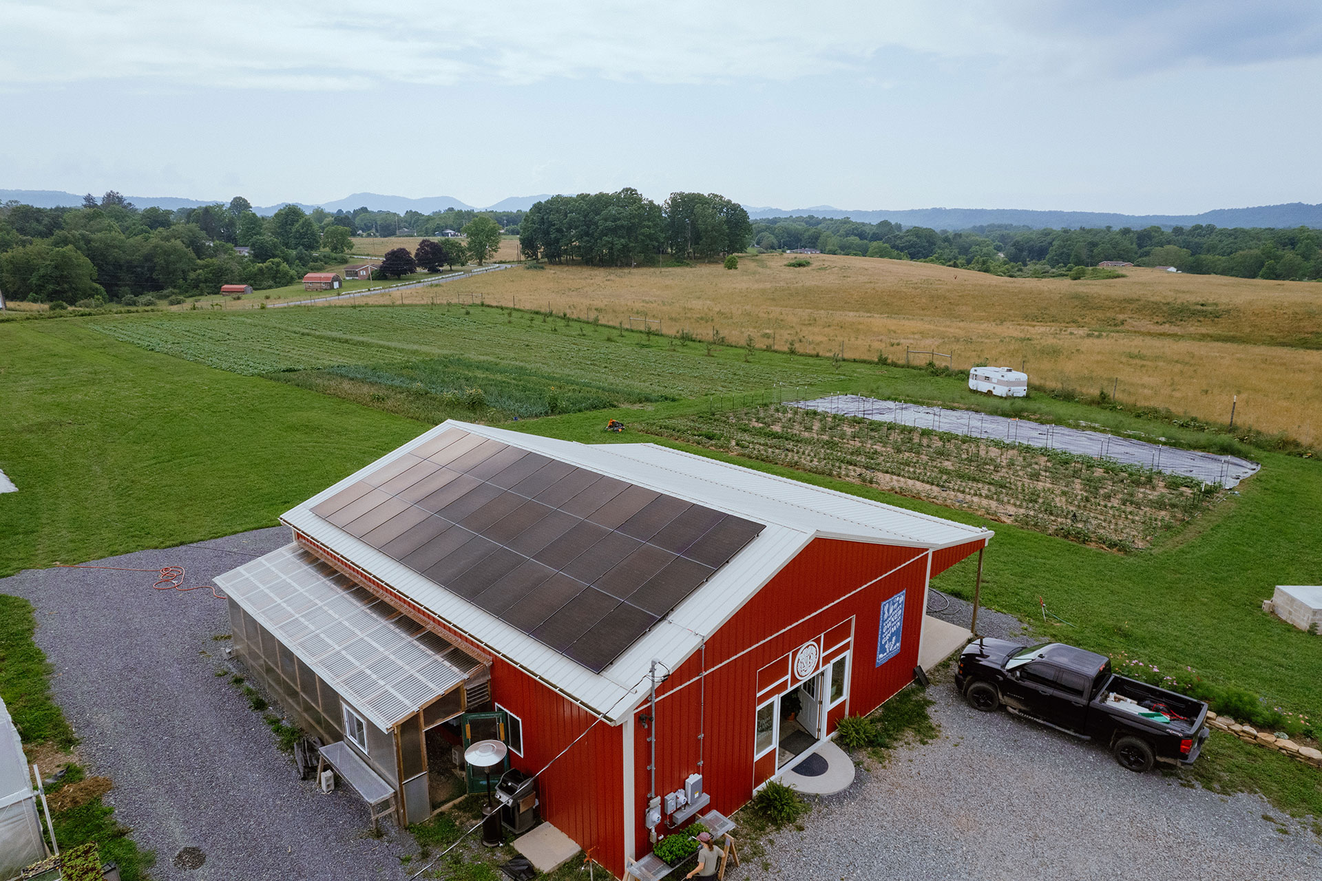 Aerial photo of a farm in rural Applachia. Barn has solar panels on top of the roof.