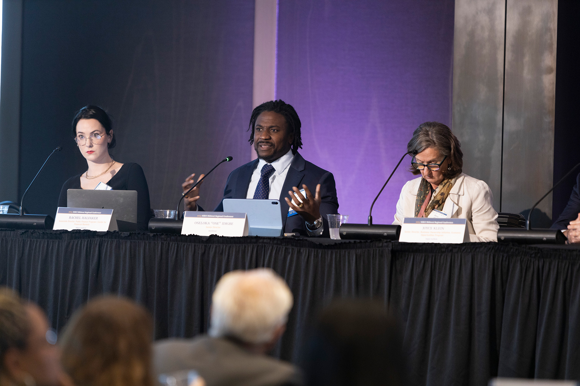 Three panelists sitting a table addressing the audience.