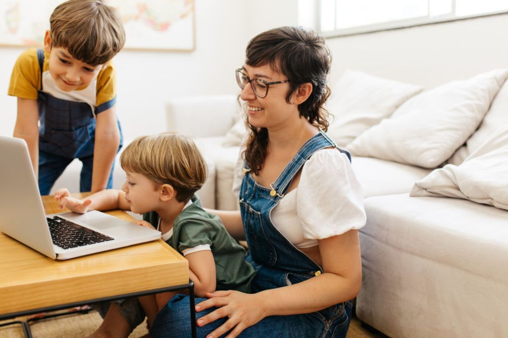 Mom and two boys using a laptop in their living room