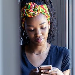 African American teenage girl uses mobile phone indoors