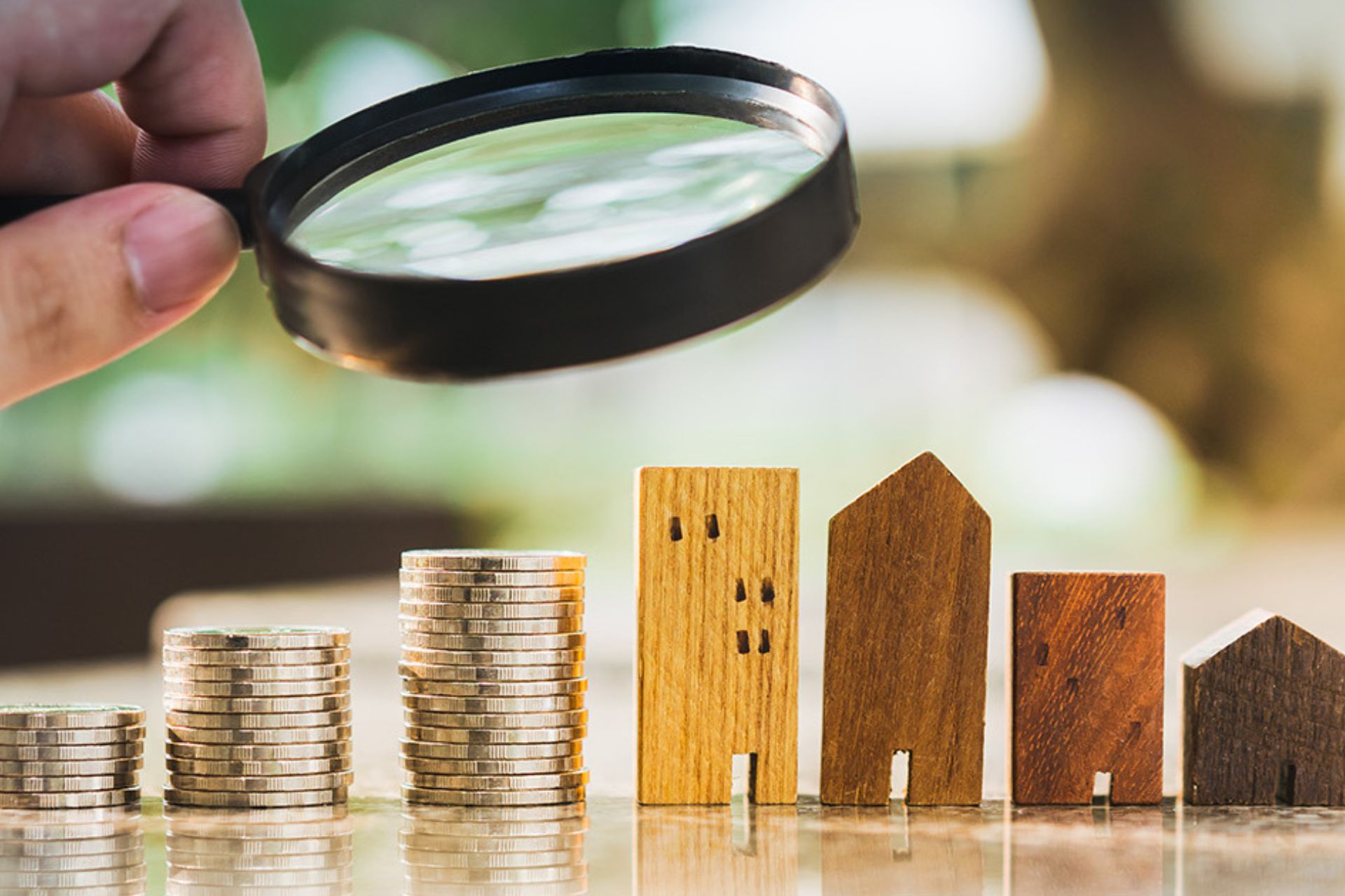 Magnifying glass over wooden building models and coins