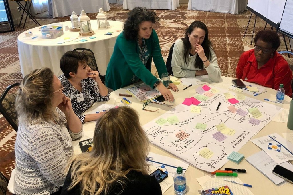 A group of people sit around a table in a planning exercise. 
