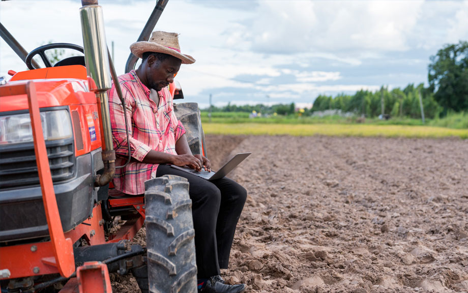 Farmer sitting on tractor while looking at laptop