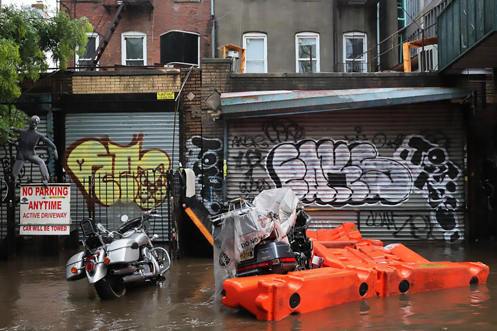 Two motorcycles parked in front of a garage in New York City surrounded by flood waters.