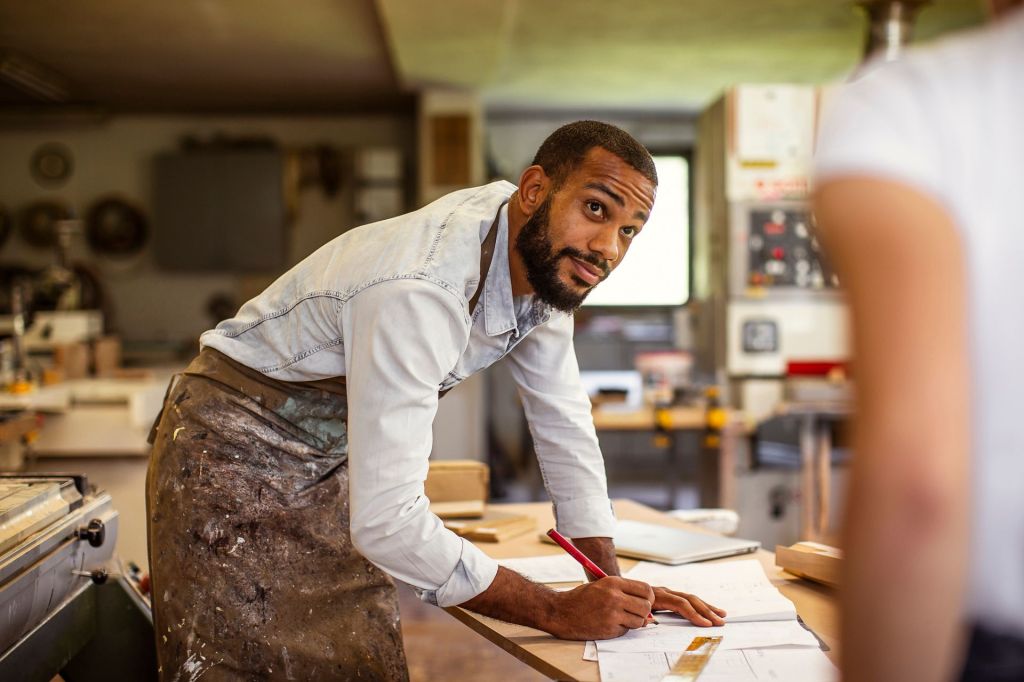 Black owned businessman leaning over table signing paperwork