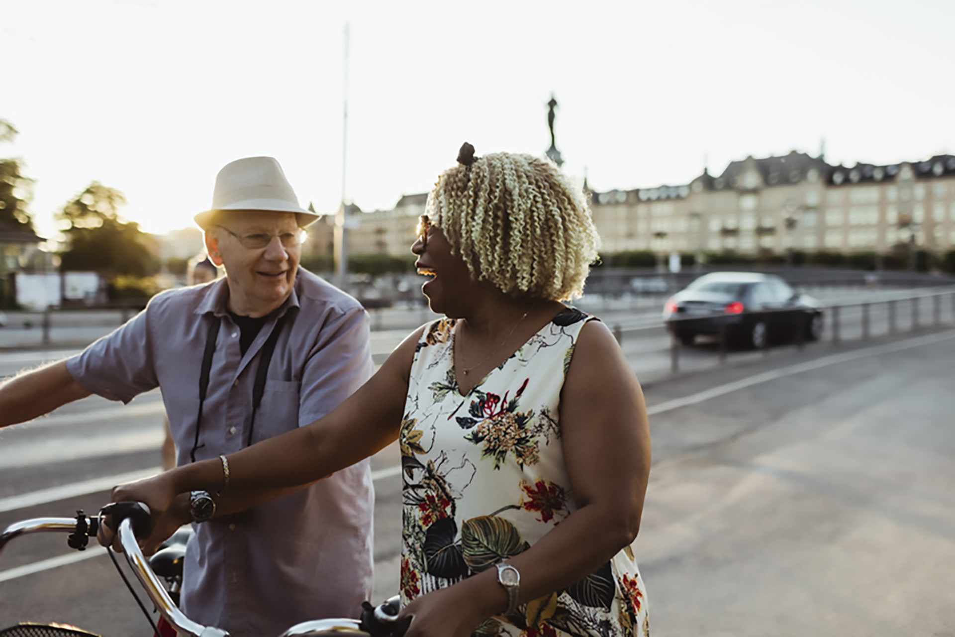 An older couple enjoying riding their bikes in an urban environment.