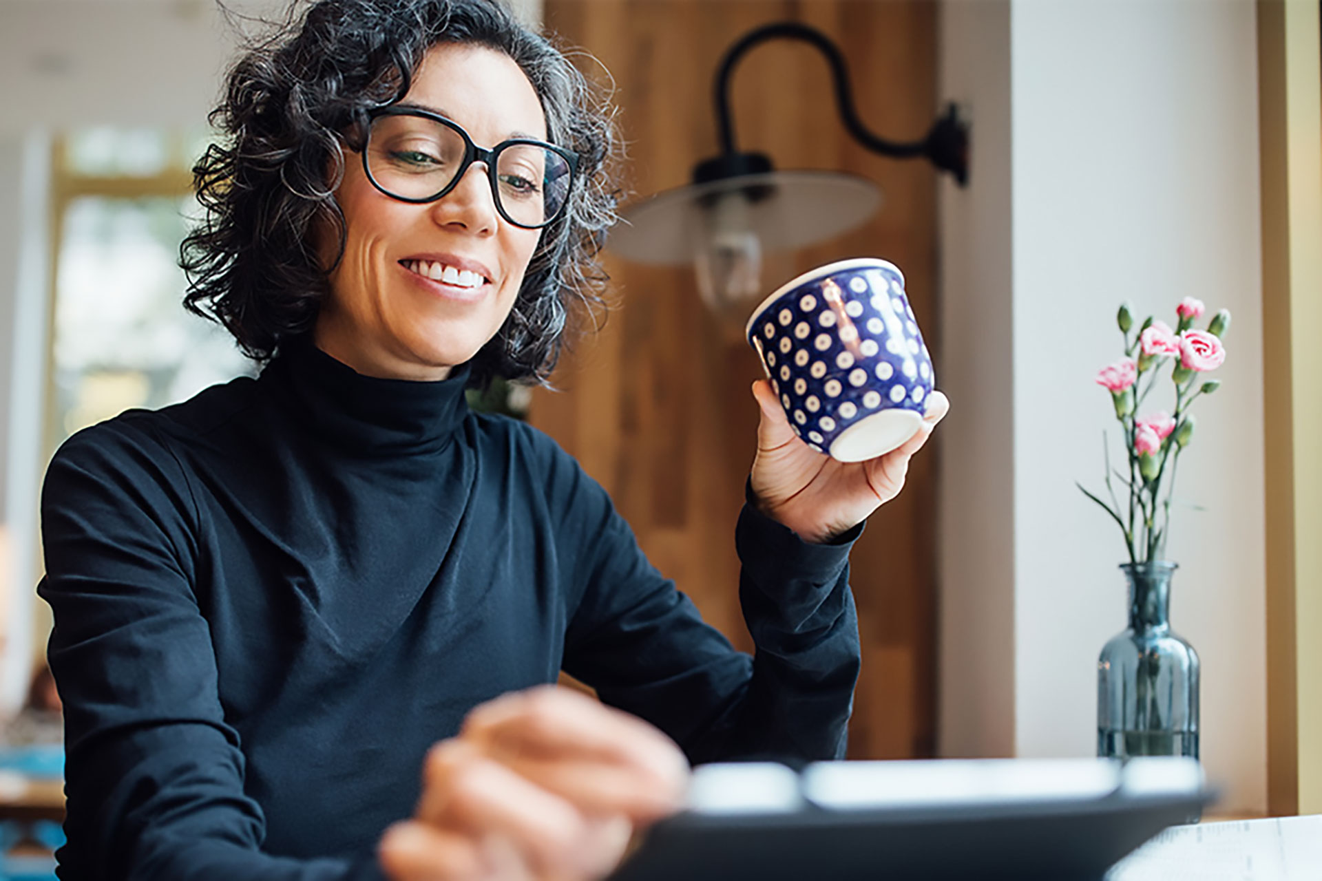 Small business owner checking emails while drinking a cup of coffee