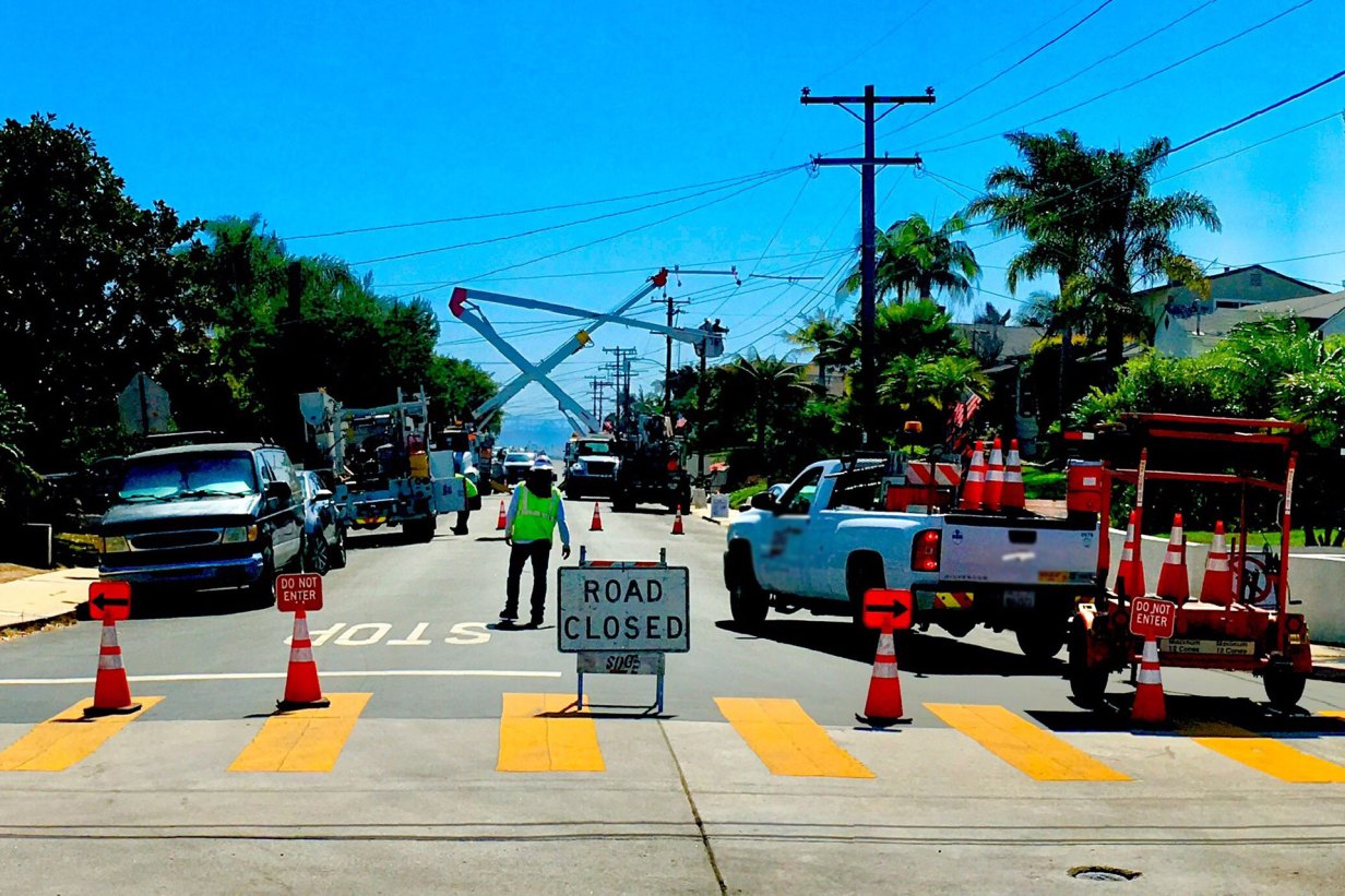 ”Road closed ” sign as a lineman crew works on power lines