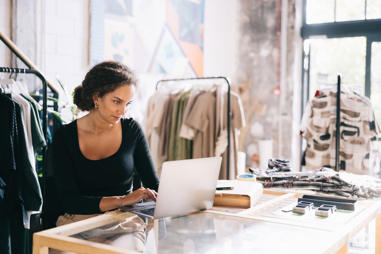 Female clothing shop owner managing her online store on a laptop