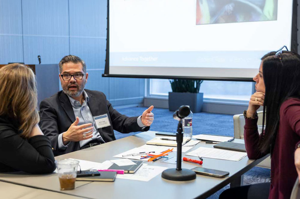 Three people sit in a conference room deep in discussion. 