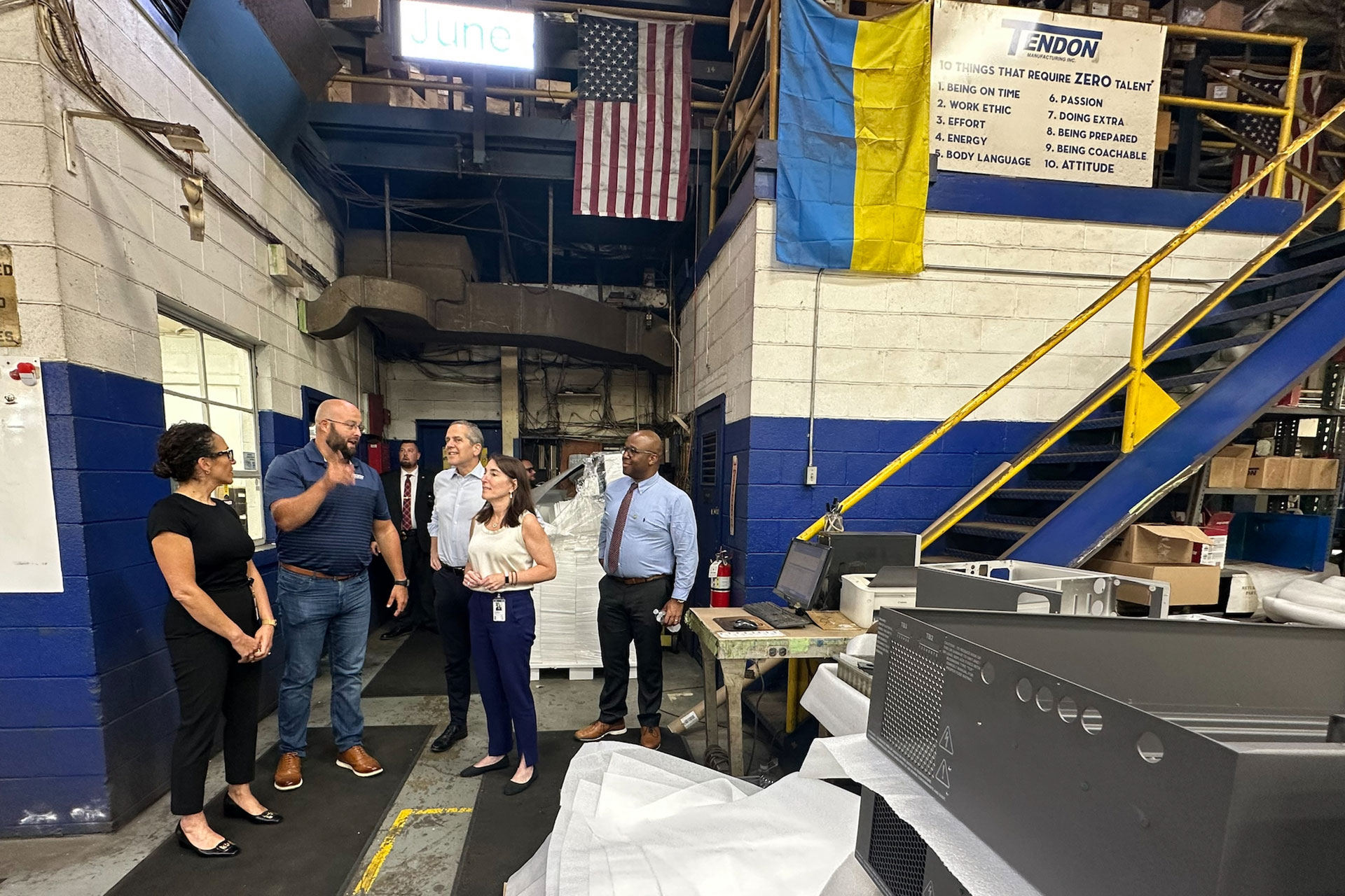 A group of people talking on the floor of a manufacturing plant.