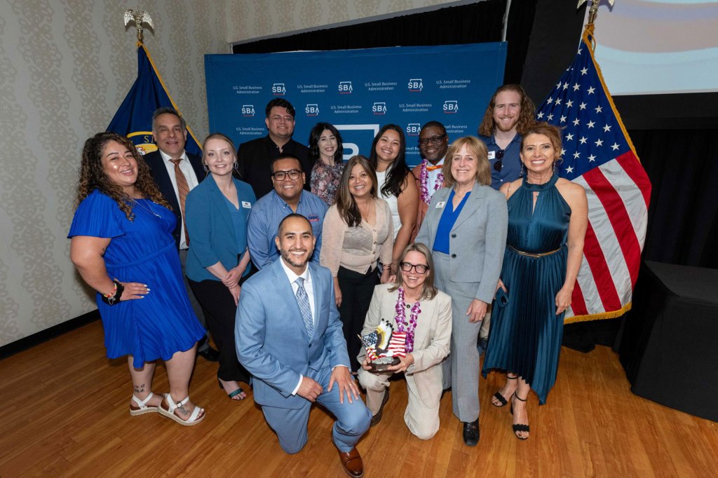 A group of people standing together with smiling faces holding a U.S. Small Business Administration Award.