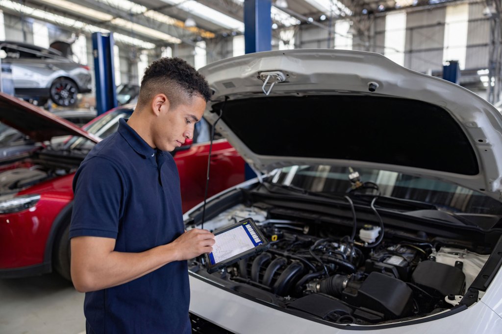 Mechanic using a AI application to diagnose the problem with a modern car at the garage