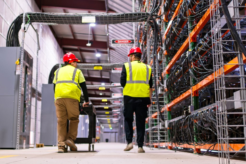 Two technicians walking past racks of equipment in a data center